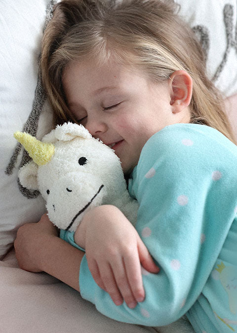 Child hugging a unicorn plush