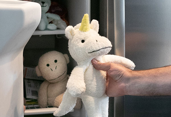 Unicorn plush being placed into a freezer