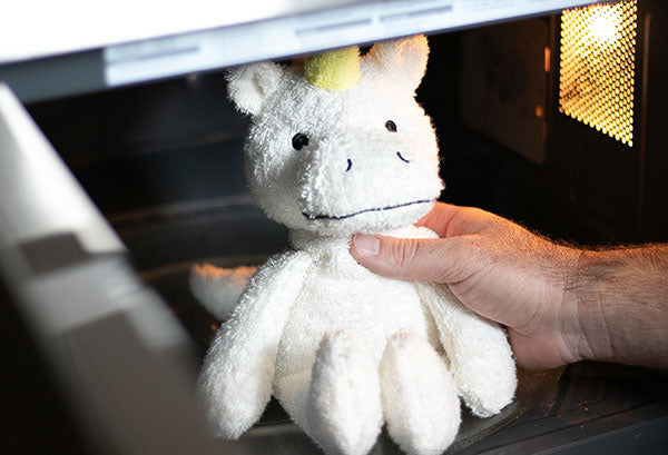 Unicorn plush being warmed in a microwave